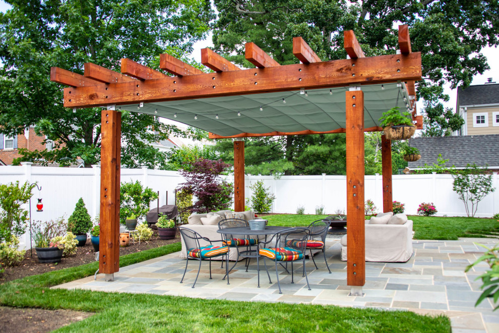 Modelo de patio clásico en patio trasero con adoquines de hormigón y pérgola