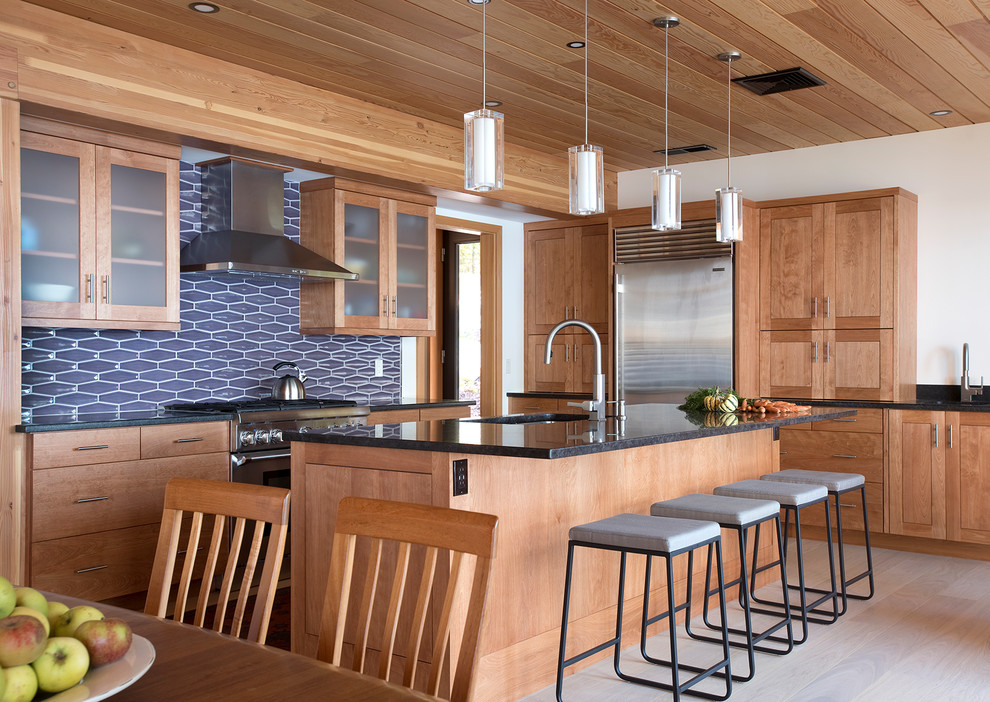 This is an example of a country eat-in kitchen in Other with a single-bowl sink, medium wood cabinets, stainless steel appliances, light hardwood floors, with island and beige floor.