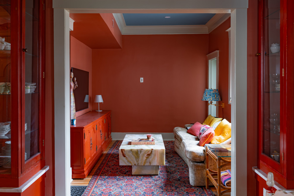 This is an example of an enclosed family room in Austin with red walls, medium hardwood floors, a wall-mounted tv, brown floor and recessed.