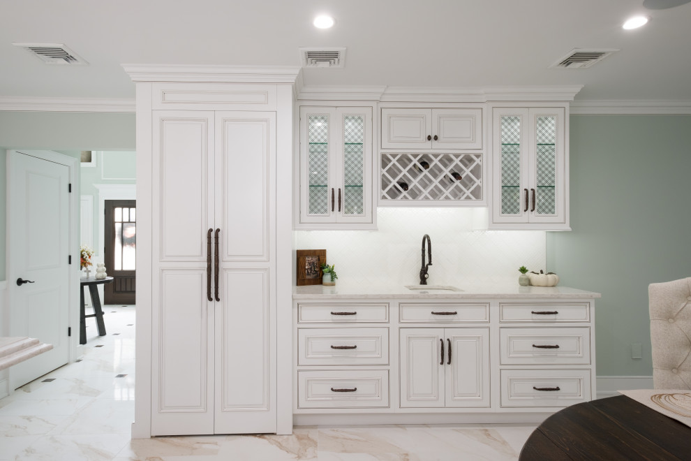 This is an example of a mid-sized traditional l-shaped eat-in kitchen in New York with a farmhouse sink, beaded inset cabinets, white cabinets, quartz benchtops, white splashback, panelled appliances, marble floors, with island, white floor and white benchtop.