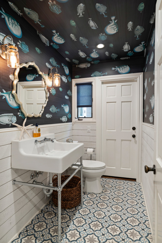 Design ideas for a beach style powder room in Los Angeles with blue walls, a console sink, multi-coloured floor, decorative wall panelling and wallpaper.
