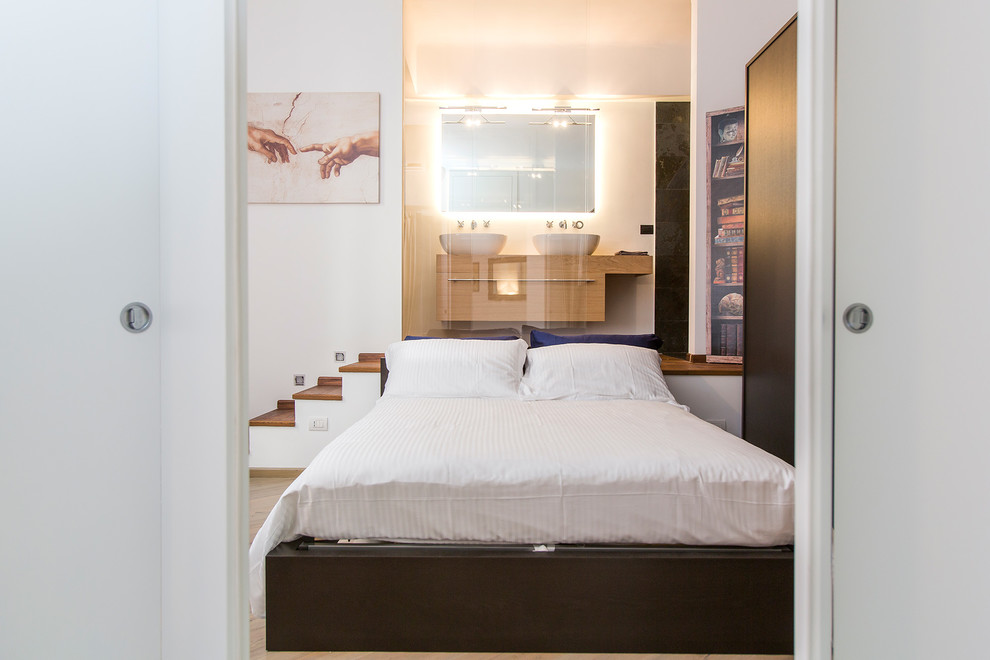 This is an example of a small contemporary master bedroom in Milan with white walls and medium hardwood floors.