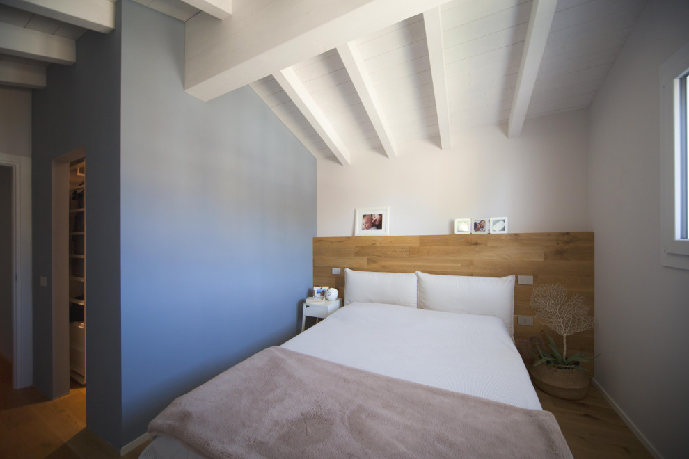 Immagine di una camera matrimoniale scandinava di medie dimensioni con pareti blu, pavimento in legno massello medio, travi a vista e pareti in legno