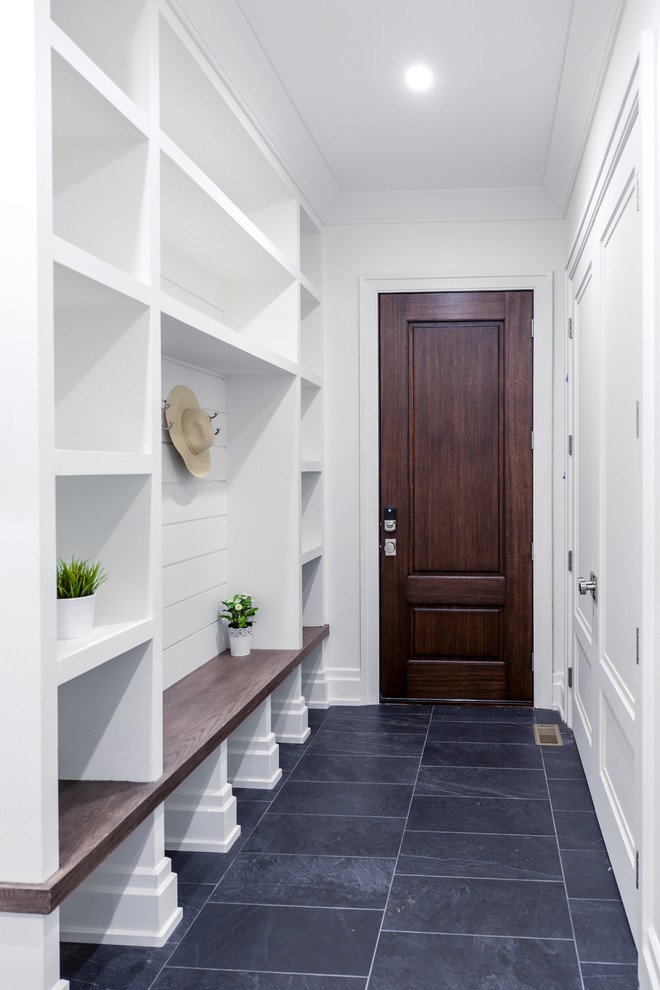 This is an example of a mid-sized country mudroom in New York with white walls, slate floors, a single front door, a dark wood front door and black floor.