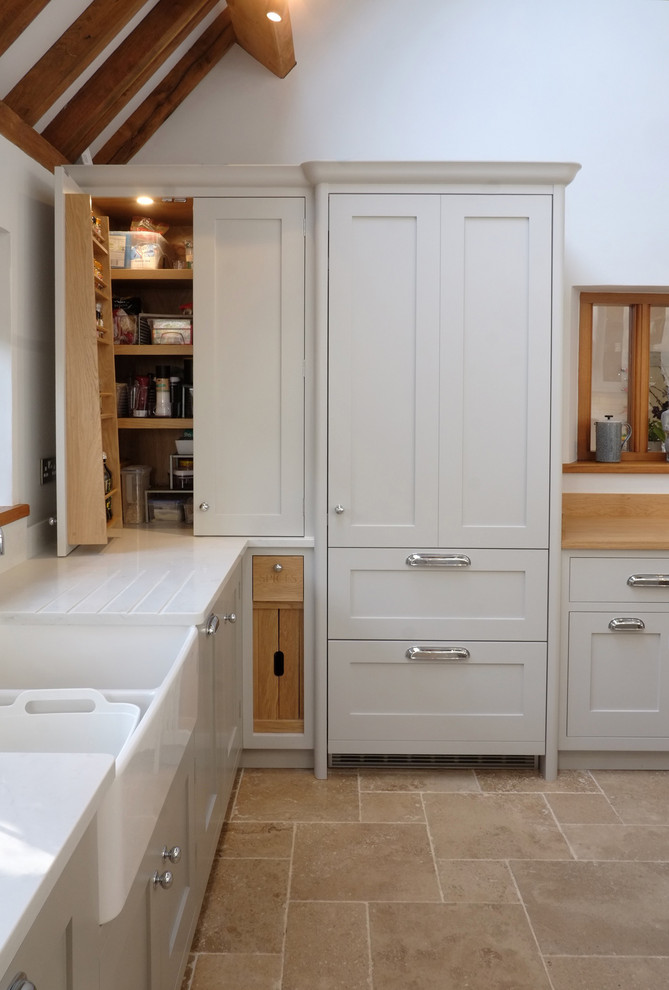 Photo of a small country kitchen in Other with a farmhouse sink, shaker cabinets, grey cabinets, quartzite benchtops, white splashback, ceramic splashback, stainless steel appliances, limestone floors, with island, beige floor and white benchtop.
