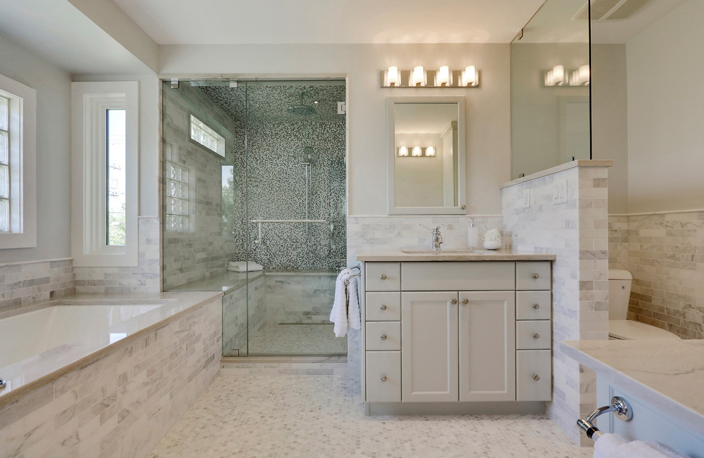 Transitional gray tile mosaic tile floor and beige floor alcove shower photo in Calgary with flat-panel cabinets, gray cabinets, an undermount tub, a two-piece toilet, beige walls, an undermount sink, a hinged shower door and beige countertops