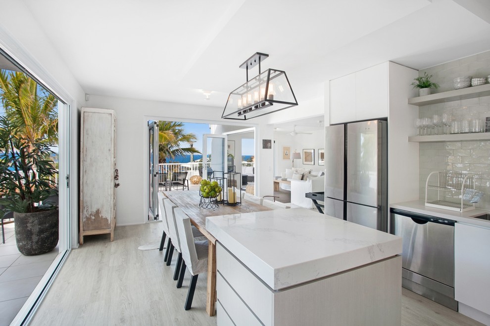 This is an example of a mid-sized beach style l-shaped eat-in kitchen in Sunshine Coast with a drop-in sink, ceramic splashback, stainless steel appliances and with island.