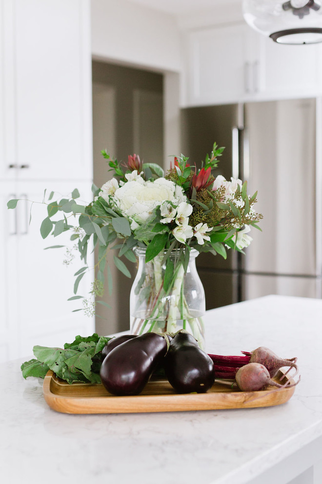 Inspiration for a mid-sized transitional u-shaped medium tone wood floor and brown floor open concept kitchen remodel with an undermount sink, shaker cabinets, white cabinets, quartz countertops, white backsplash, porcelain backsplash, stainless steel appliances, an island and white countertops