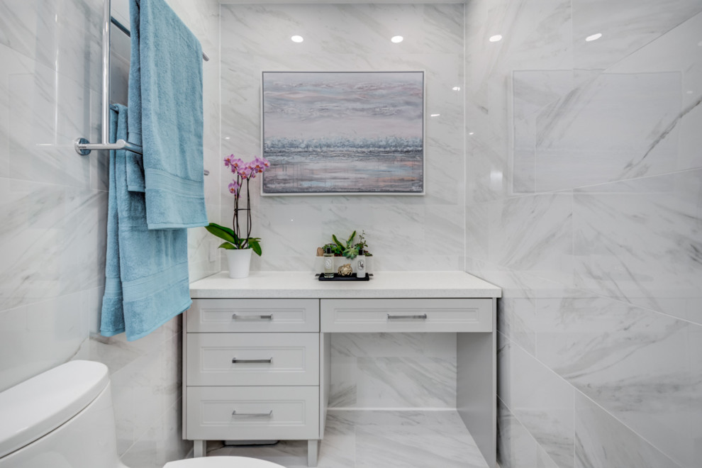Design ideas for a mid-sized contemporary master bathroom in Toronto with shaker cabinets, grey cabinets, an alcove shower, a one-piece toilet, white tile, porcelain tile, white walls, porcelain floors, an undermount sink, engineered quartz benchtops, white floor, a sliding shower screen and white benchtops.