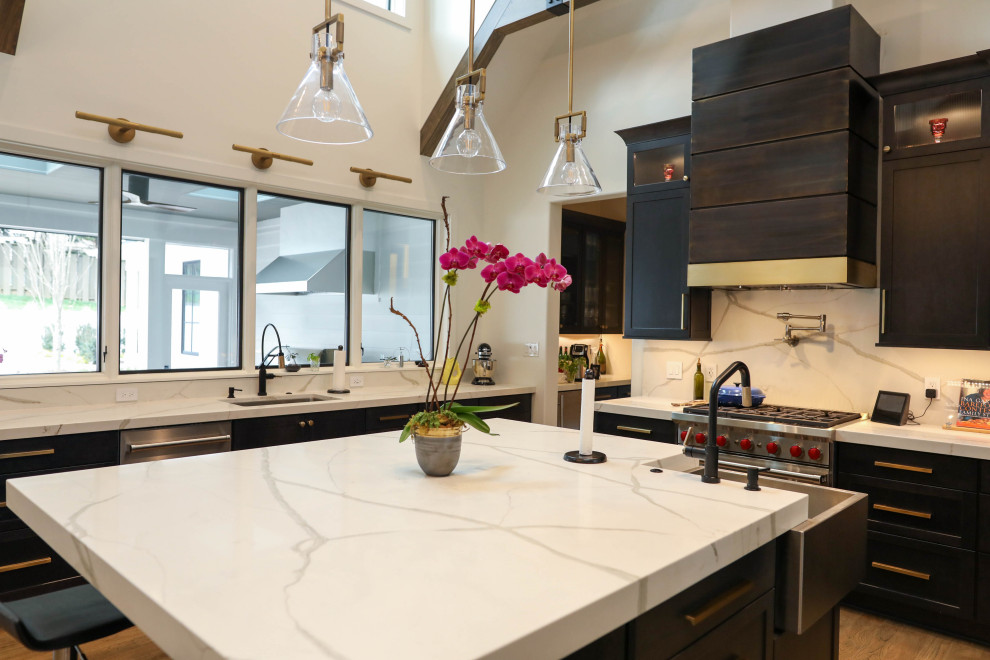 Inspiration for a large transitional u-shaped light wood floor open concept kitchen remodel with a farmhouse sink, flat-panel cabinets, dark wood cabinets, quartz countertops, white backsplash, quartz backsplash, stainless steel appliances, an island and white countertops