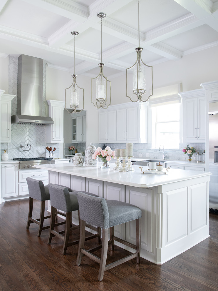 Traditional kitchen in Dallas with a farmhouse sink, raised-panel cabinets, white cabinets, grey splashback, stainless steel appliances, dark hardwood floors, with island, brown floor and white benchtop.