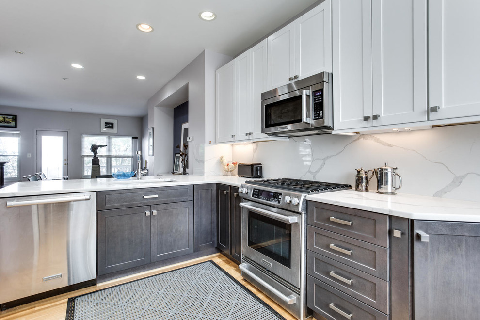 Mid-sized modern l-shaped kitchen in DC Metro with an undermount sink, shaker cabinets, white cabinets, quartz benchtops, white splashback, stainless steel appliances, light hardwood floors, a peninsula and beige floor.