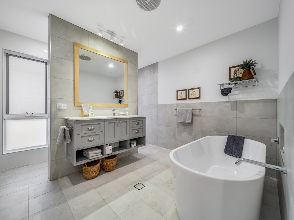 This is an example of a transitional master bathroom in Newcastle - Maitland with shaker cabinets, grey cabinets, a freestanding tub, gray tile, white walls, an undermount sink, engineered quartz benchtops, grey floor, white benchtops, a single vanity and a floating vanity.