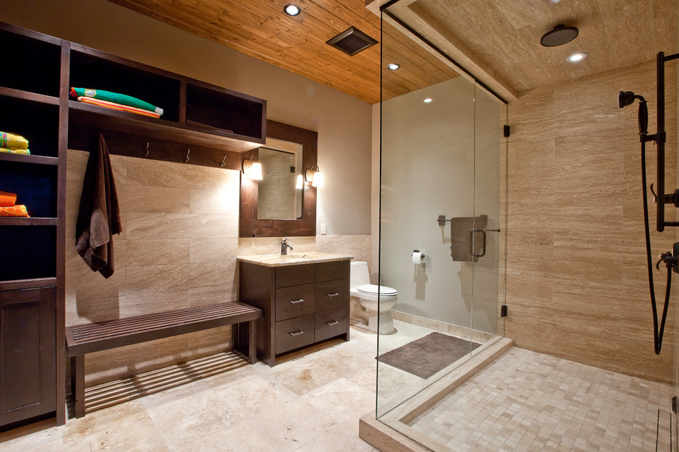 Design ideas for a contemporary bathroom in Calgary with flat-panel cabinets, dark wood cabinets, a corner shower, beige tile and travertine.