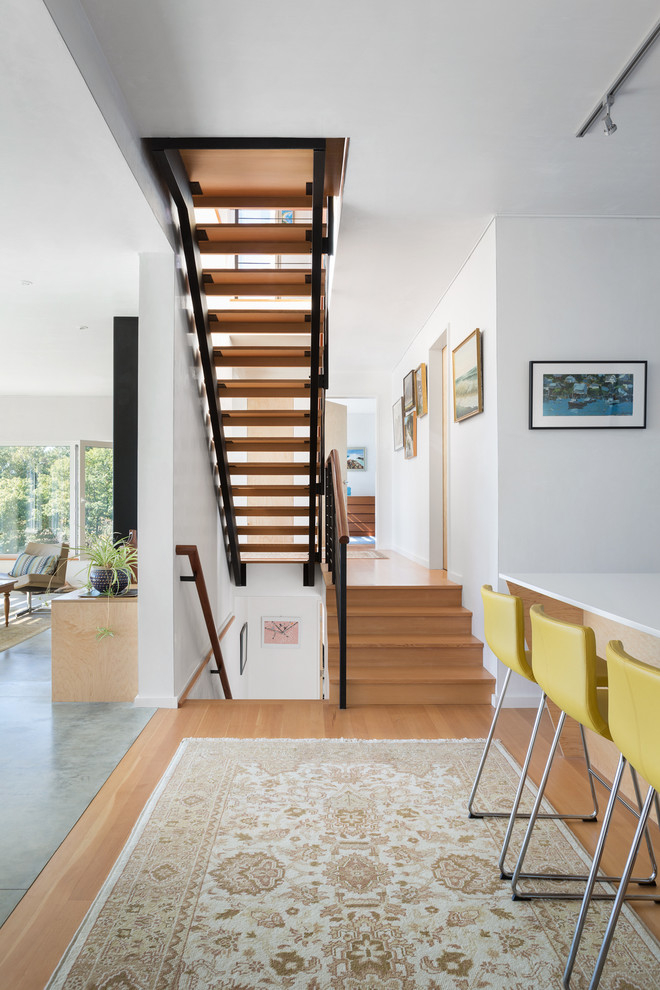 Photo of a mid-sized contemporary hallway in Portland Maine with white walls and light hardwood floors.