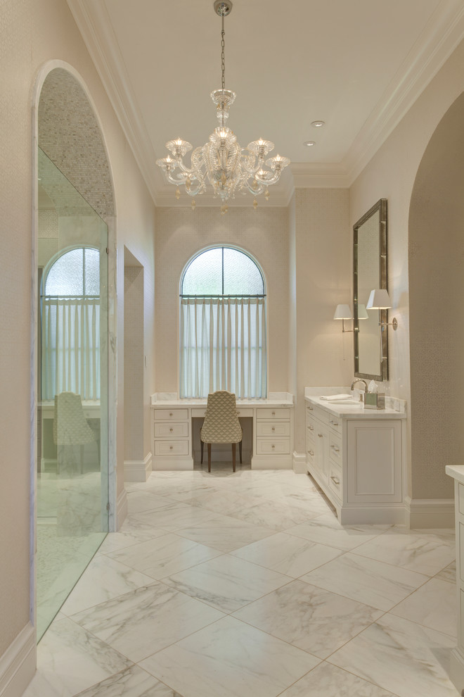 Photo of an expansive mediterranean master bathroom in Dallas with an undermount sink, beaded inset cabinets, white cabinets, marble benchtops, a freestanding tub, a double shower, a one-piece toilet, white tile, stone slab, white walls and marble floors.