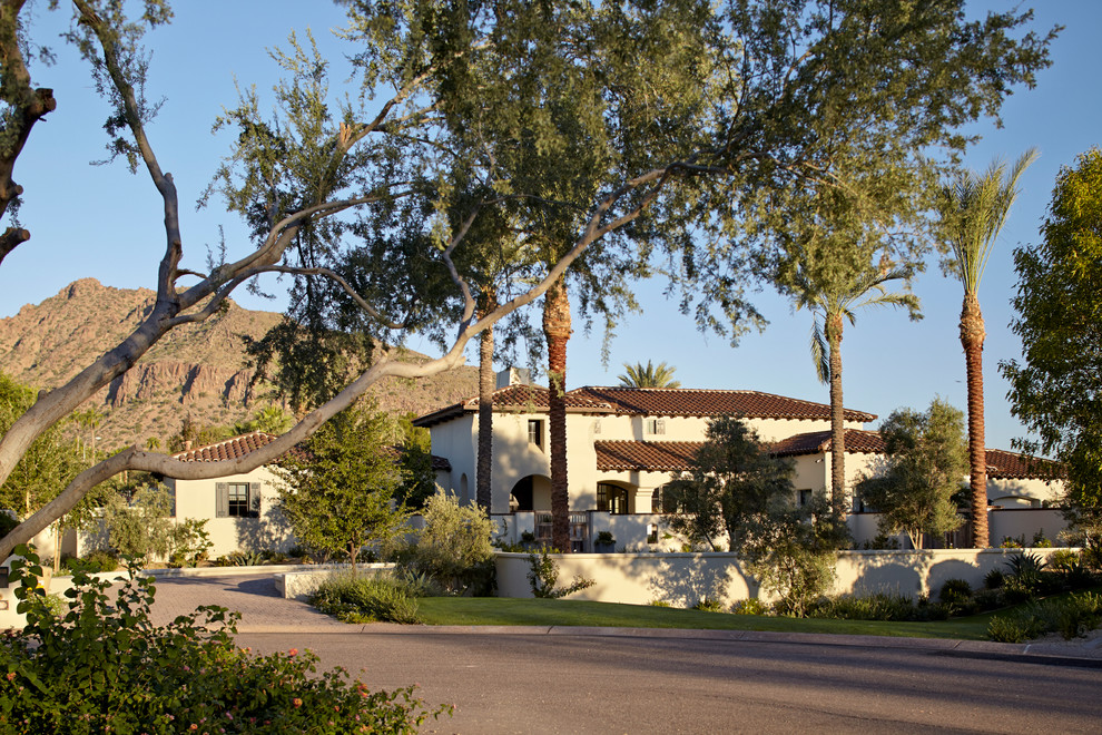 This is an example of a large mediterranean two-storey adobe beige exterior in Phoenix with a hip roof.