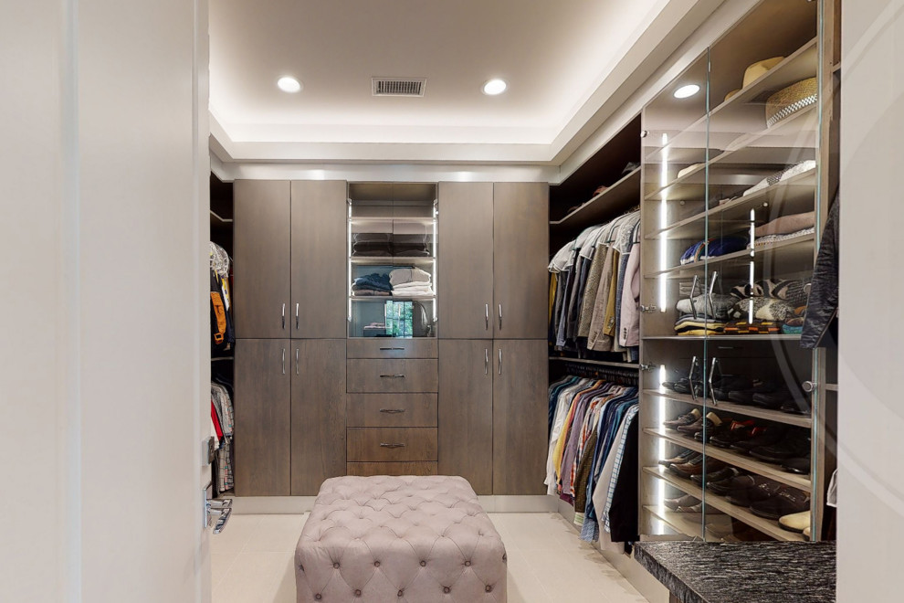 Diseño de armario vestidor de hombre moderno grande con armarios con paneles lisos, puertas de armario grises, suelo de baldosas de porcelana, suelo beige y casetón