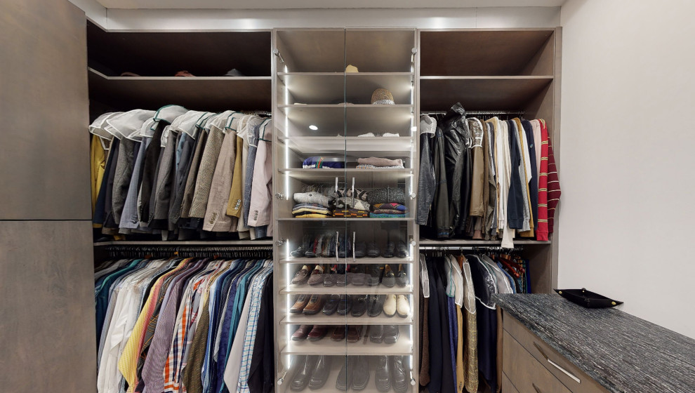 Diseño de armario vestidor de hombre minimalista grande con armarios con paneles lisos, puertas de armario grises, suelo de baldosas de porcelana, suelo beige y casetón