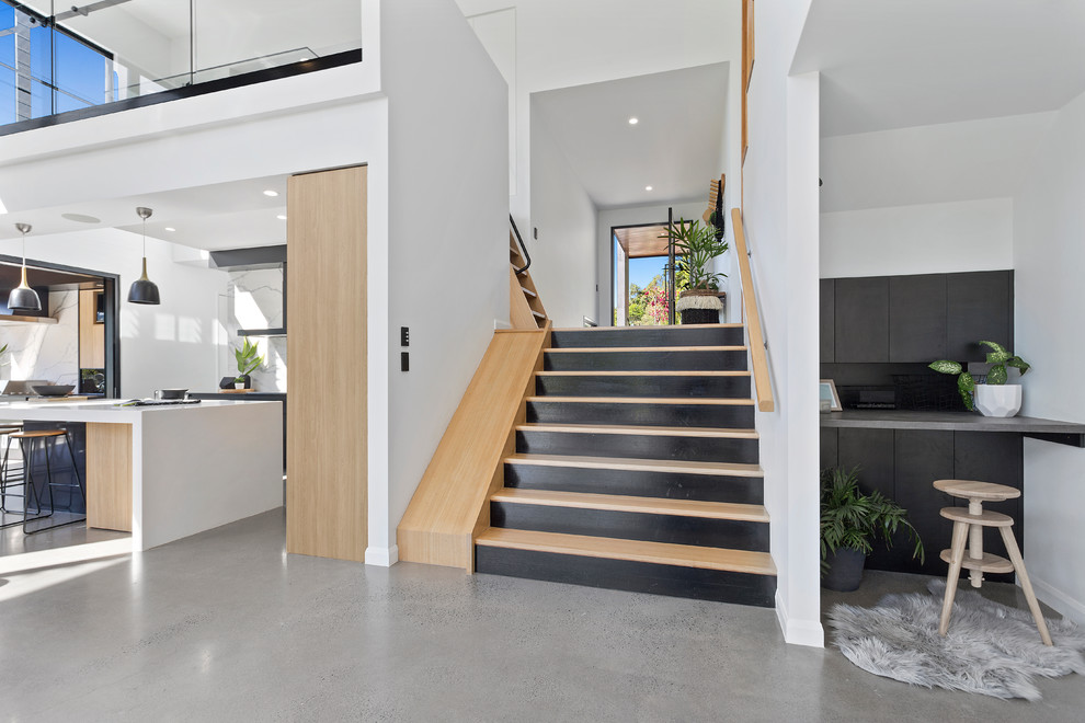 Large contemporary wood u-shaped staircase in Sunshine Coast with painted wood risers and wood railing.