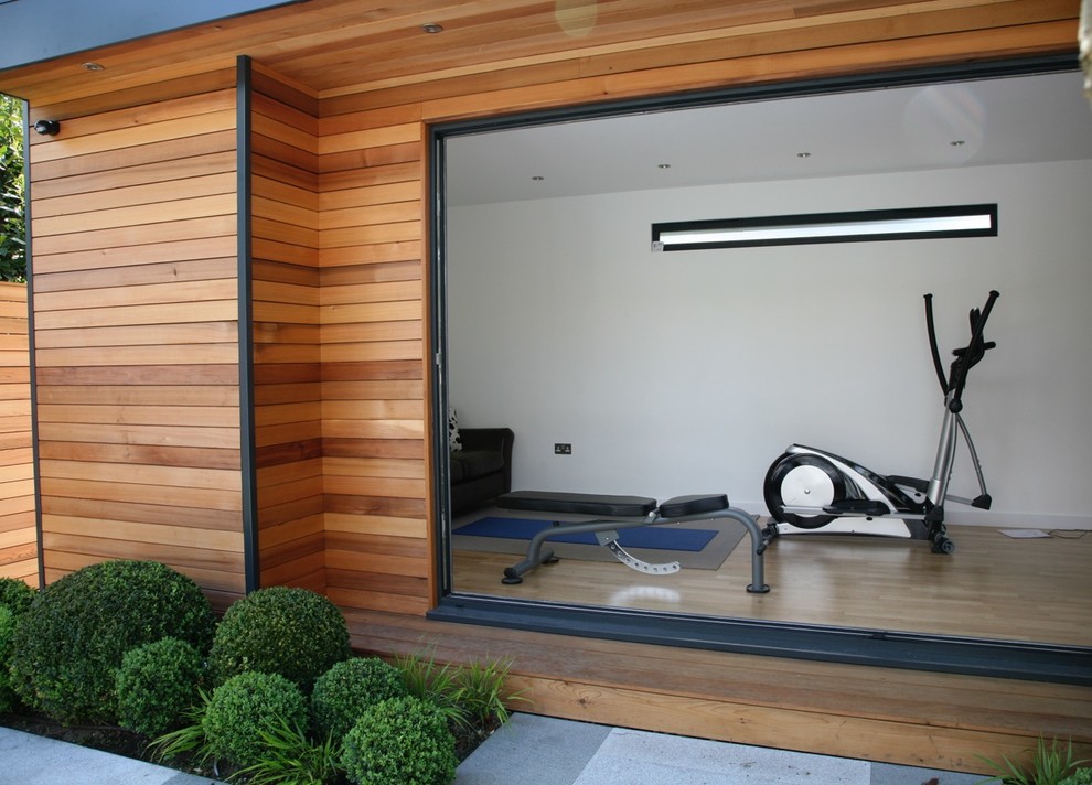 Inspiration for a large contemporary home gym in West Midlands with white walls and light hardwood floors.