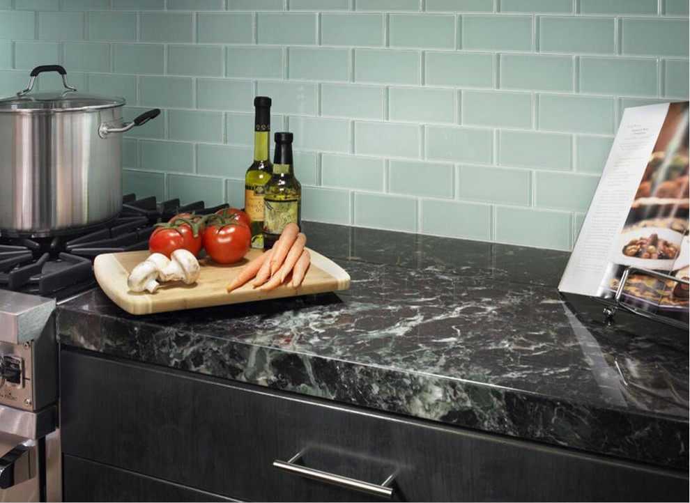 Inspiration for a transitional medium tone wood floor kitchen remodel with flat-panel cabinets, white cabinets, solid surface countertops, blue backsplash, glass tile backsplash and stainless steel appliances