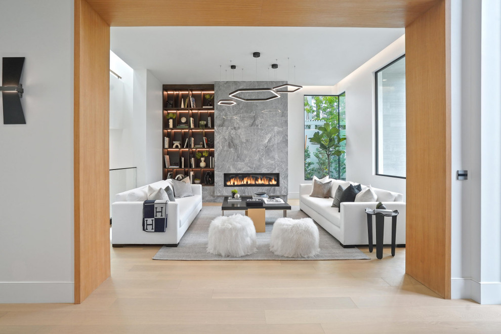 Großes, Repräsentatives, Abgetrenntes Modernes Wohnzimmer mit weißer Wandfarbe, hellem Holzboden, Kamin, Kaminumrandung aus Stein, braunem Boden und Holzwänden in Los Angeles