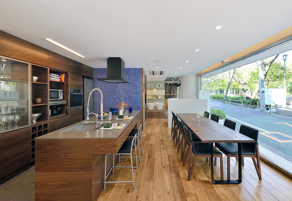 Photo of a contemporary single-wall eat-in kitchen in Tokyo with a double-bowl sink, flat-panel cabinets, medium wood cabinets, glass benchtops, stainless steel appliances, light hardwood floors and with island.