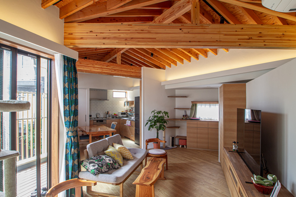 Ejemplo de salón abierto escandinavo de tamaño medio con paredes blancas, suelo de madera clara, televisor independiente, suelo beige y vigas vistas