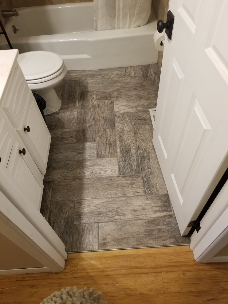 Photo of a small arts and crafts 3/4 bathroom in Other with louvered cabinets, white cabinets, an alcove tub, a shower/bathtub combo, a two-piece toilet, beige tile, ceramic tile, beige walls, medium hardwood floors, brown floor, a shower curtain and white benchtops.
