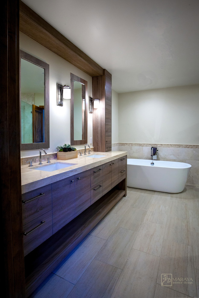 Design ideas for a mid-sized contemporary master bathroom in Santa Barbara with an undermount sink, flat-panel cabinets, medium wood cabinets, limestone benchtops, a freestanding tub, an alcove shower, a two-piece toilet, beige tile, stone slab, beige walls and marble floors.