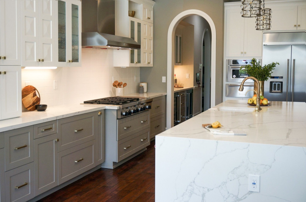 Inspiration for a large contemporary l-shaped open plan kitchen in Orange County with an undermount sink, shaker cabinets, white cabinets, marble benchtops, white splashback, subway tile splashback, stainless steel appliances, dark hardwood floors, with island, brown floor and white benchtop.