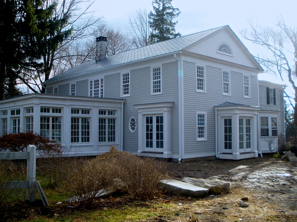 Traditional two-storey grey house exterior in New York with wood siding, a gable roof and a shingle roof.