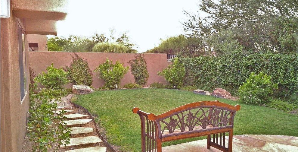 Large traditional backyard patio in Phoenix with a vertical garden, natural stone pavers and a roof extension.