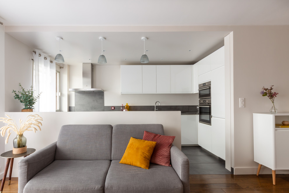 This is an example of a large traditional l-shaped eat-in kitchen in Paris with a single-bowl sink, flat-panel cabinets, white cabinets, laminate benchtops, grey splashback, stainless steel appliances, with island and grey benchtop.