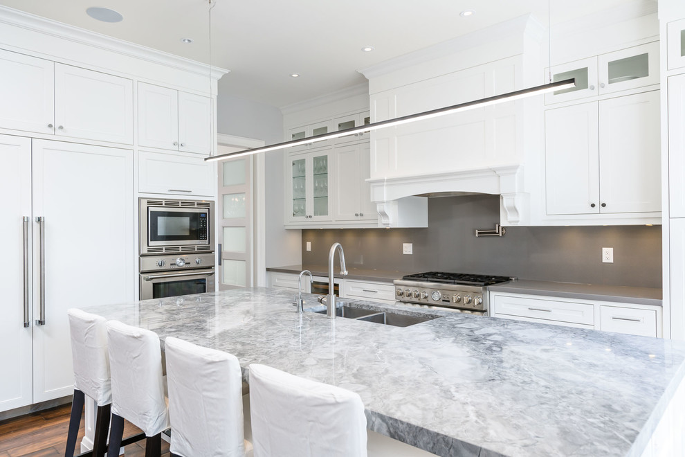Photo of a large transitional u-shaped separate kitchen in Toronto with a double-bowl sink, shaker cabinets, white cabinets, quartzite benchtops, stainless steel appliances, dark hardwood floors, with island and brown floor.