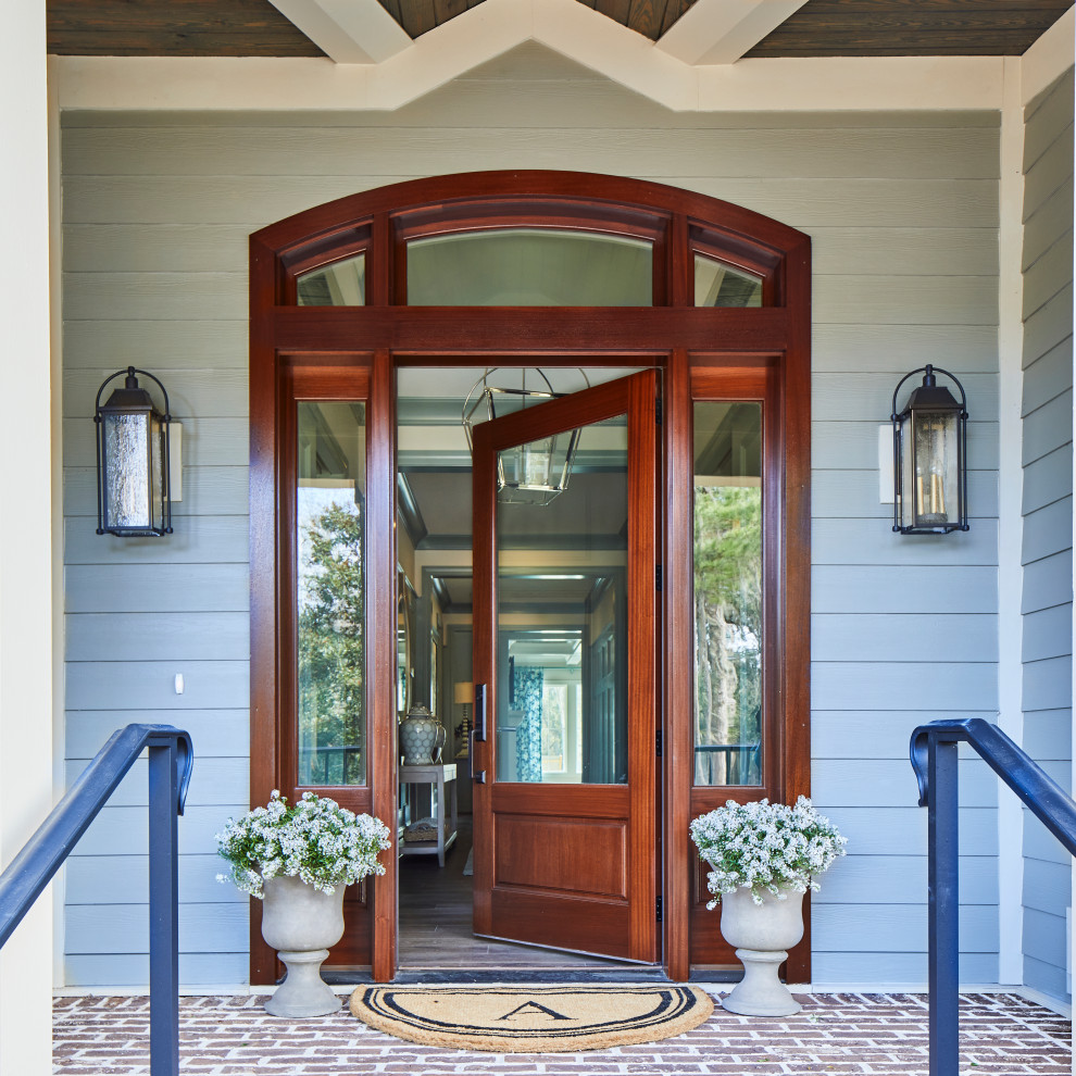 Cette image montre une grande entrée traditionnelle avec un mur beige, un sol en brique, une porte simple, une porte en bois foncé, un sol rouge et un plafond voûté.