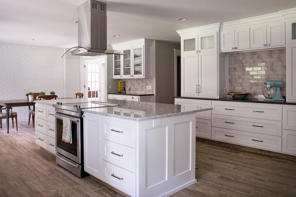 This is an example of a large arts and crafts u-shaped eat-in kitchen in Grand Rapids with an undermount sink, shaker cabinets, white cabinets, quartzite benchtops, beige splashback, subway tile splashback, stainless steel appliances, porcelain floors and with island.