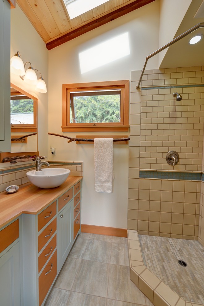 Photo of a small beach style 3/4 bathroom in San Diego with flat-panel cabinets, green cabinets, a corner shower, beige tile, ceramic tile, yellow walls, porcelain floors, a vessel sink, wood benchtops and a shower curtain.