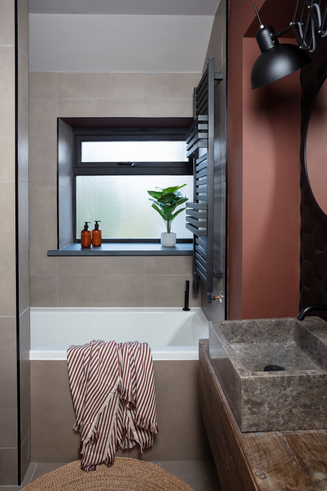 Photo of a small contemporary kids bathroom in Other with a drop-in tub, black tile, orange walls, porcelain floors, a console sink, wood benchtops, beige floor and brown benchtops.