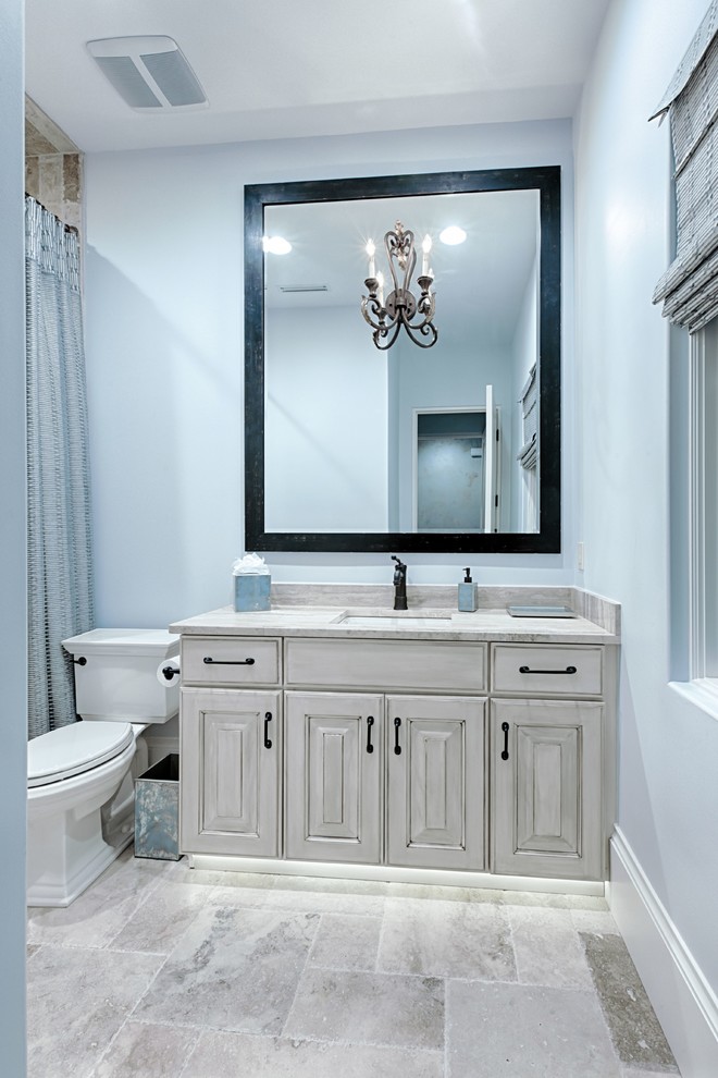 Design ideas for a mid-sized mediterranean 3/4 bathroom in Miami with raised-panel cabinets, beige cabinets, an alcove tub, an alcove shower, a two-piece toilet, beige tile, porcelain tile, blue walls, porcelain floors, an undermount sink, granite benchtops, beige floor and a hinged shower door.