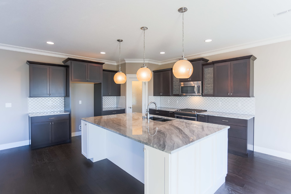Mid-sized transitional l-shaped dark wood floor open concept kitchen photo in Seattle with an undermount sink, shaker cabinets, dark wood cabinets, granite countertops, white backsplash, porcelain backsplash, stainless steel appliances and an island