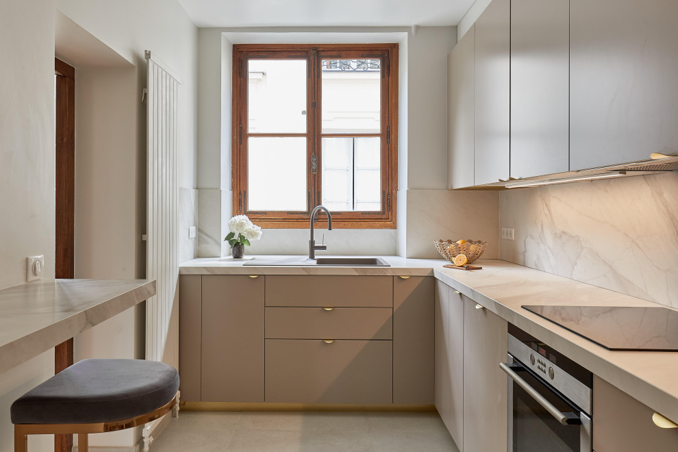 Inspiration for a contemporary u-shaped separate kitchen in Paris with flat-panel cabinets, a drop-in sink, beige cabinets, white splashback, stone slab splashback, stainless steel appliances, beige floor and white benchtop.