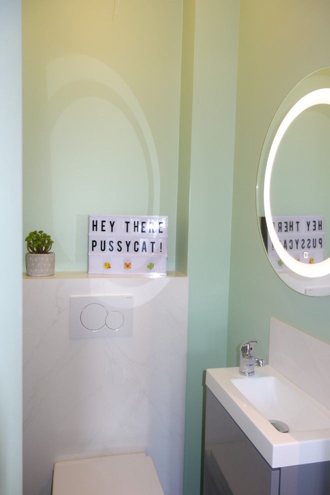 Design ideas for a small contemporary powder room in Nice with a wall-mount toilet, white tile, marble, green walls, ceramic floors, a wall-mount sink, black floor, white benchtops, flat-panel cabinets, grey cabinets and quartzite benchtops.