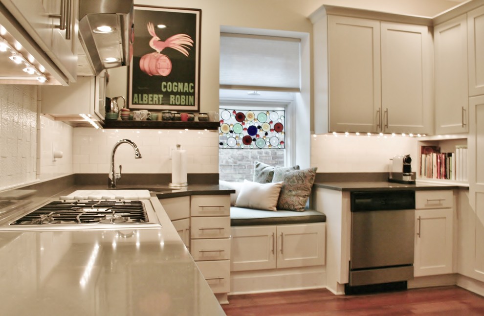 Example of a large transitional u-shaped light wood floor and brown floor enclosed kitchen design in Chicago with an undermount sink, shaker cabinets, white cabinets, quartz countertops, white backsplash, subway tile backsplash, stainless steel appliances and no island