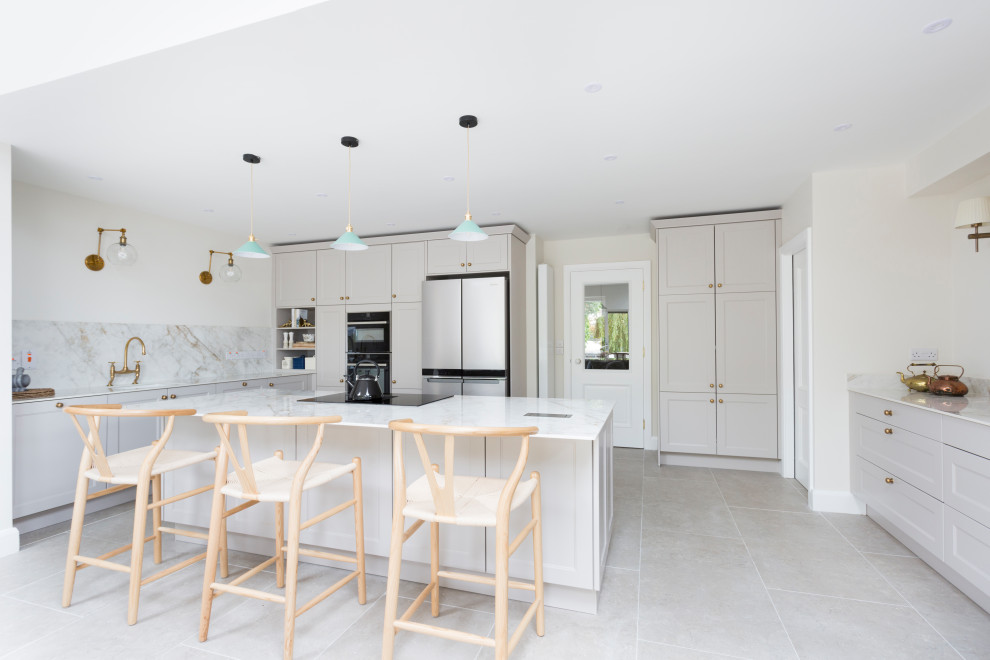 Photo of a mid-sized transitional l-shaped open plan kitchen in Dublin with recessed-panel cabinets, grey cabinets, quartzite benchtops, white splashback, with island and white benchtop.