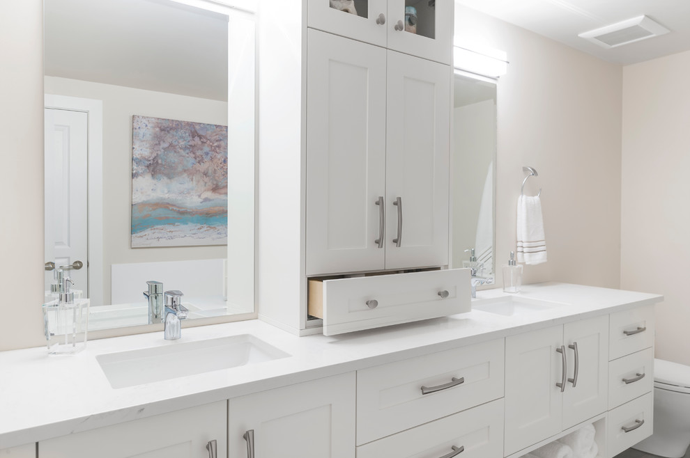 Photo of a mid-sized transitional master bathroom in Vancouver with shaker cabinets, white cabinets, a freestanding tub, a corner shower, a one-piece toilet, white tile, ceramic tile, beige walls, ceramic floors, an undermount sink and engineered quartz benchtops.