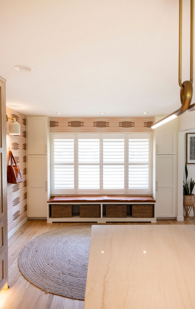 Large mudroom in Denver with wallpaper, light hardwood floors, a white front door and white walls.