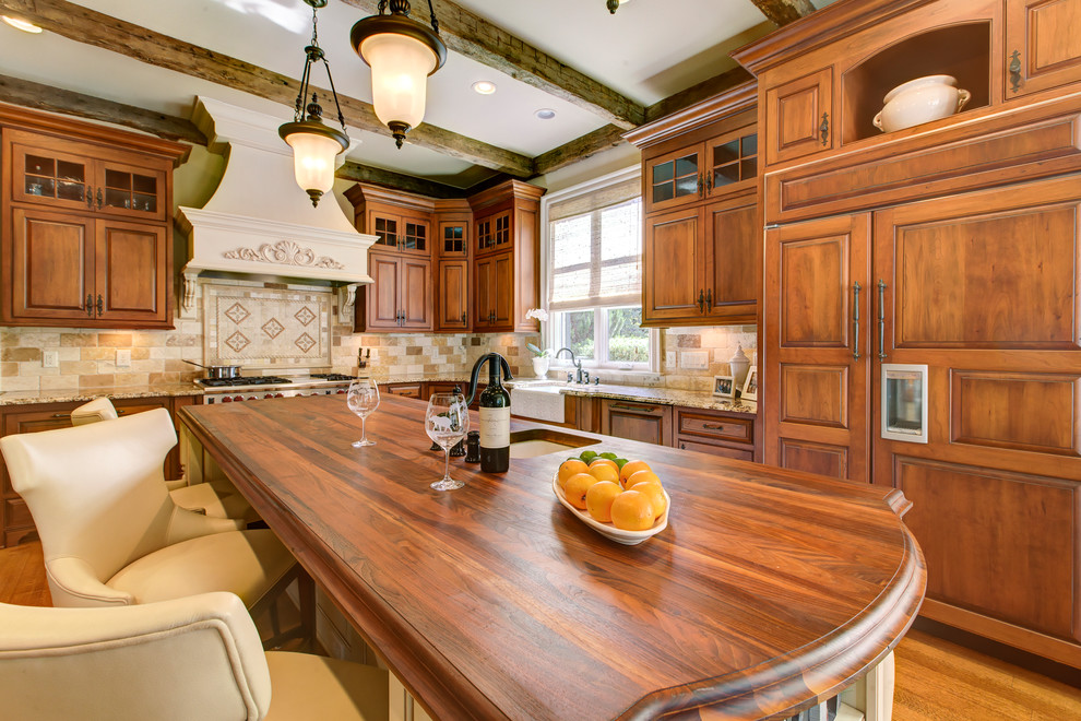 Mid-sized traditional l-shaped open plan kitchen in Raleigh with a farmhouse sink, raised-panel cabinets, medium wood cabinets, granite benchtops, beige splashback, stone tile splashback, panelled appliances, light hardwood floors and with island.