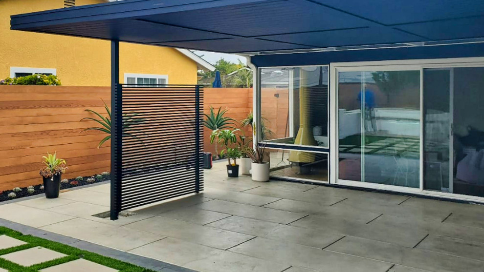 Example of a mid-sized 1950s backyard stone patio design in Orange County with a pergola